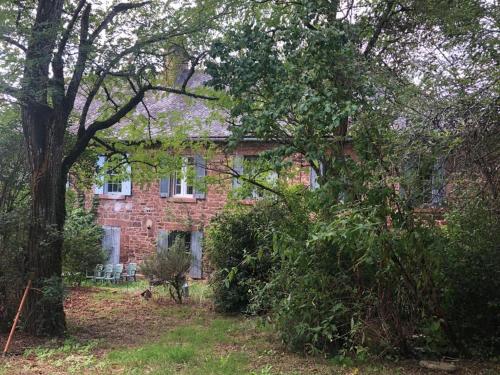una vieja casa de ladrillo con árboles delante de ella en Manoir de Salleviale, en Conques-en-Rouergue