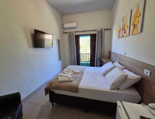a bedroom with a large bed with white sheets and pillows at Hotel Serra do Mar in Paranaguá