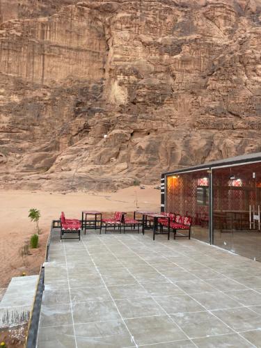 a patio with tables and benches in front of a mountain at Spirit of the Badia camp in Disah