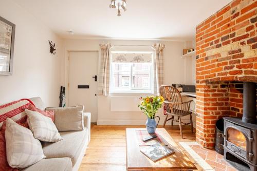 a living room with a couch and a brick fireplace at Charming Georgian flint cottage in Bury Saint Edmunds