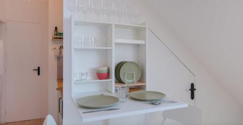 a white cabinet with two plates and a mirror at Le Perchoir du marché - Appartement pour 2 personnes in Saint-Nazaire