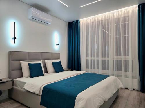 ein Schlafzimmer mit einem großen Bett mit blauen Kissen in der Unterkunft Belvedere Apart 2, parking in Iwano-Frankiwsk