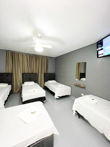 Cette chambre comprend 3 lits et une télévision murale. dans l'établissement Hostel Anprado #12, à Guarulhos