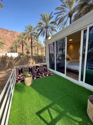un patio con erba verde, un letto e palme di caravan alula a Al Ula