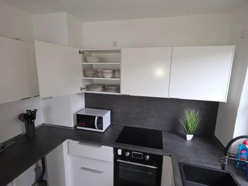 een kleine keuken met witte kasten en een magnetron bij Nestwerk Solide L16-02 in Biberach an der Riß