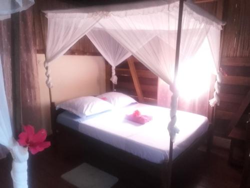 een slaapkamer met een hemelbed met witte lakens bij Antafondro Lodge in Sainte Marie