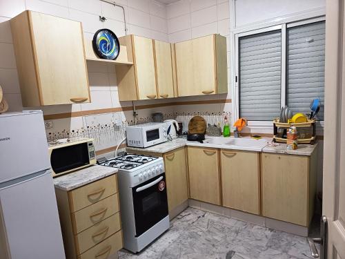 eine Küche mit Herd und Mikrowelle in der Unterkunft Eden Cozy Airport in El Aouina Station