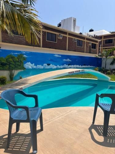two chairs sitting in front of a swimming pool at Hotel El Rincon de Don Juan in Tecolutla