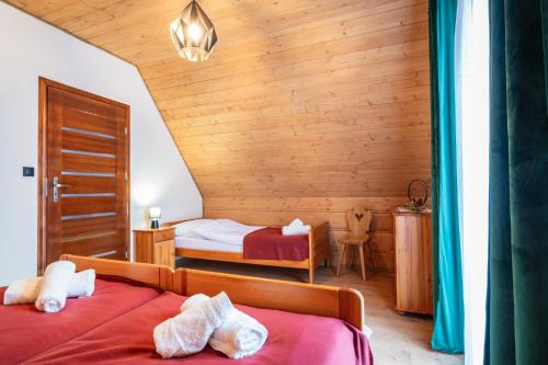 een slaapkamer met 2 bedden en een houten muur bij Burnosówka in Nowy Targ