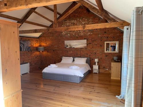 a bedroom with a bed in a brick wall at Eastfields Farm Barns in Melchbourne