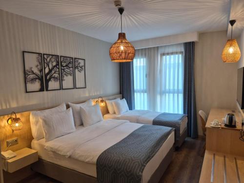 a hotel room with two beds and two windows at Güllük Uno Elegance Otel in Gulluk