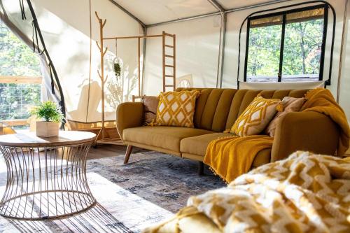 a living room with a couch and a table at The Goldfinch's Nest - Glamping Tent with AC in Rogers