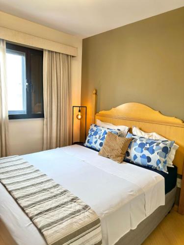 a bedroom with a large bed with blue and white pillows at Flat luxo, Janela Antirruído, Garagem, serviços in São Paulo