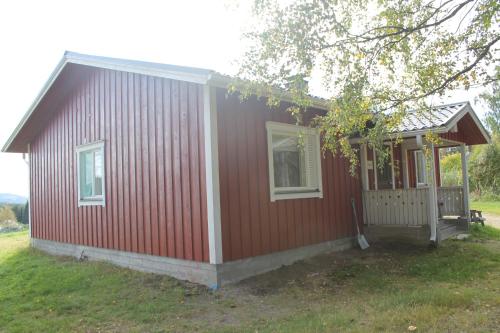 a small red house with a porch and a window at Maatilamatkailu Jänisvaara in Kolinkylä