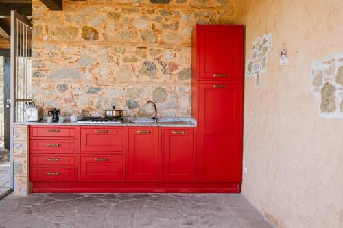 une cuisine rouge avec un évier et un mur de briques dans l'établissement Calàmi - Villa Romeo - Private Apartments with Pool, Seaview & Olive Grove, à Santa Caterina Dello Ionio Marina