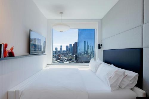 a bedroom with a large white bed and a window at citizenM Boston North Station in Boston