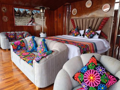 a bedroom with a bed and two couches with pillows at Brisas del Titicaca Perú in Puno