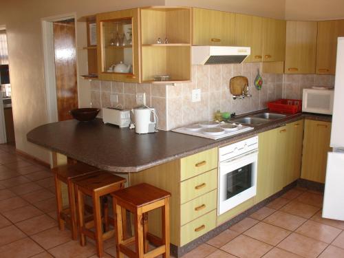 a kitchen with wooden cabinets and a black counter top at Blue Horizon Flat 8 in Jeffreys Bay