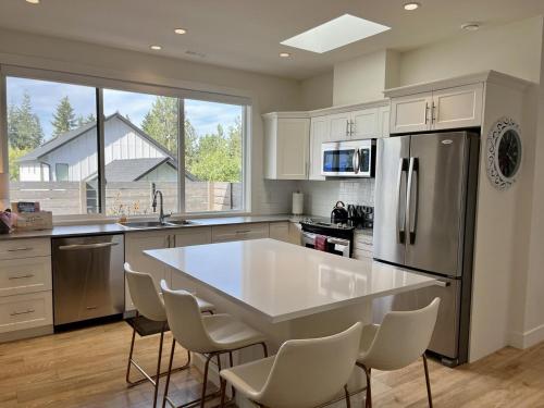 een keuken met een groot wit kookeiland met stoelen erin bij Modern, Cheerful 2 Bdrm Ohana Vacation Cottage in Kelowna