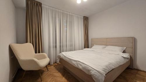 Un dormitorio con una cama blanca y una silla. en Shakespeare Central Apartment, en Craiova