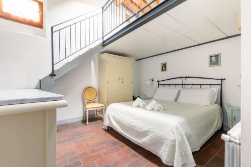 a bedroom with a white bed and a staircase at Fabio Apartments San Gimignano in San Gimignano