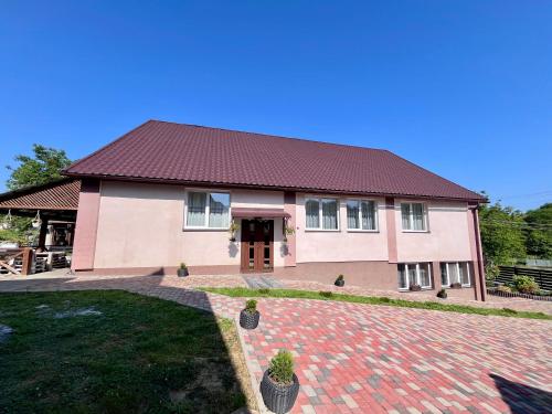 une maison avec un toit rouge et une allée en briques dans l'établissement У Лариси, à Solochyn