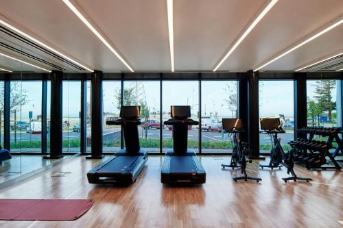 a gym with treadmills and ellipticals in a room with windows at citizenM Menlo Park in Menlo Park