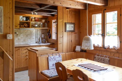 una cucina con pareti in legno, tavolo e sedie di Le Petit Mayen a Châtel-Saint-Denis