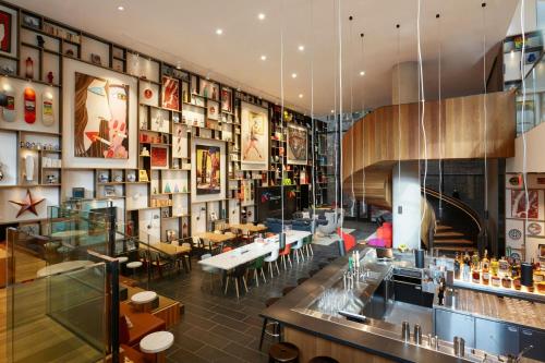 a restaurant with a bar and tables and chairs at citizenM New York Bowery in New York
