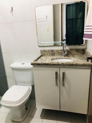 a bathroom with a toilet and a sink and a mirror at Home Confort in Garanhuns