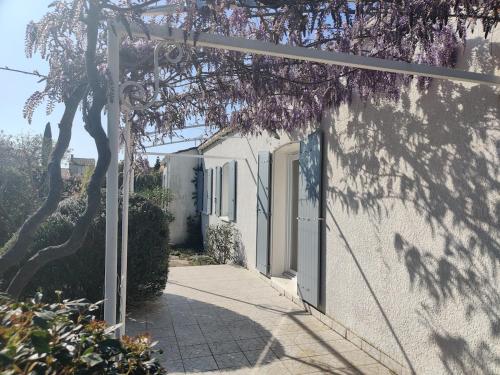 ein weißes Gebäude mit einer Tür und einem Baum in der Unterkunft Villa Caroux in Bédarieux
