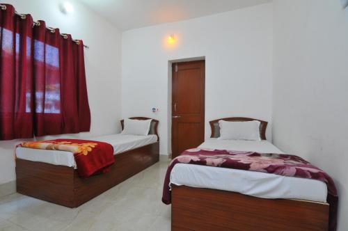 two beds in a room with red curtains at Rama Guest House in Bodh Gaya