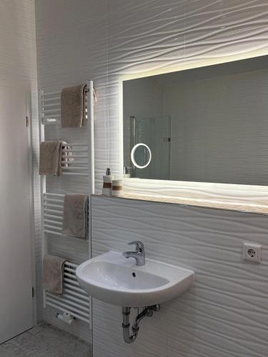 a white bathroom with a sink and a mirror at Sleep2Fly Hamburg-Airport in Hamburg