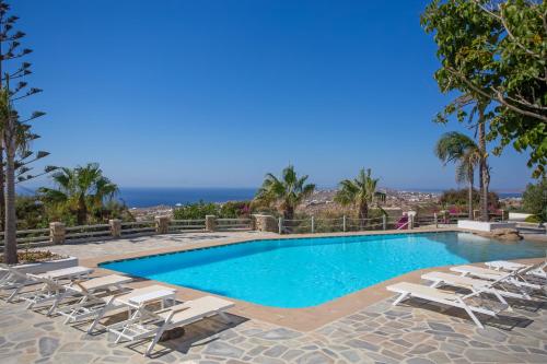 a swimming pool with chaise lounge chairs and a resort at Villa Scorpio by Bestofmikonos in Mikonos