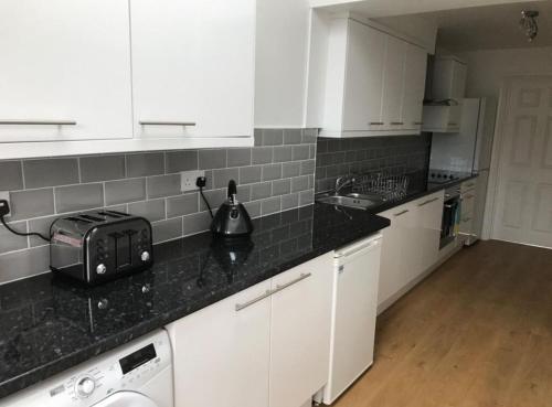 a kitchen with white cabinets and a black counter top at Cosy 4 Bed House In Solihull Near Town-NEC-BHX in Sheldon
