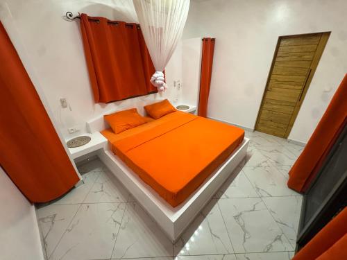 - une chambre avec un lit orange et une salle de bains dans l'établissement Villa Warang, à Warang