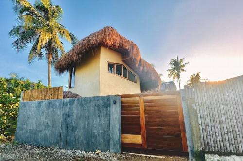 a house with a thatched roof behind a fence at Villa Isleñas - Solar, Starlink, Pool in General Luna