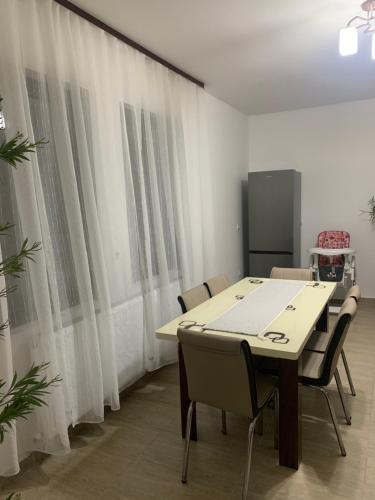 Una mesa y sillas en una habitación con cortinas. en M Dey, en Vişeu de Sus