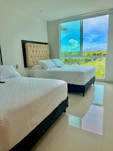 two beds in a bedroom with a large window at Apartamento de lujo con vista al mar en Karibana in Cartagena de Indias