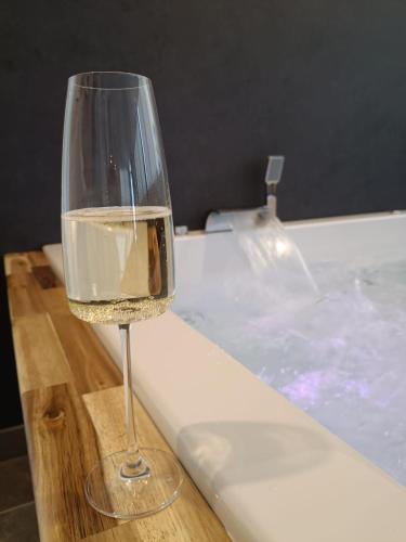 a glass of wine sitting next to a bath tub at Luxus-Apartment Champagner & Spa in Herford
