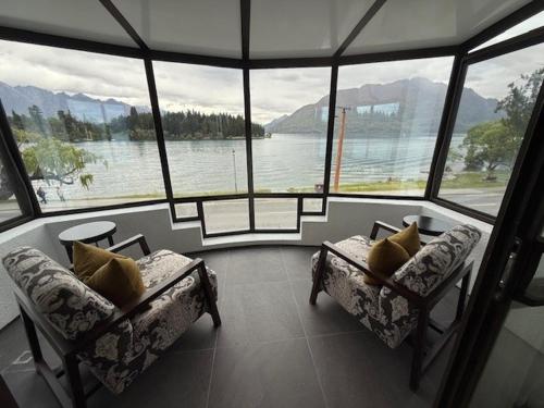 a room with two couches and a view of the water at Queenstown House Lakeside in Queenstown
