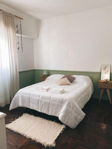 una camera da letto con un letto con lenzuola bianche e un tappeto di Departamento Constitución a Tandil