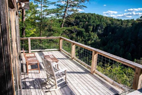 a wooden deck with chairs and tables on it at The Cliffside Cabin - Stunning Views in Red River Gorge in Rogers