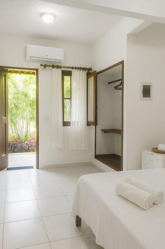 a white bedroom with a bed and a mirror at Morada Toniatti in Barra Grande