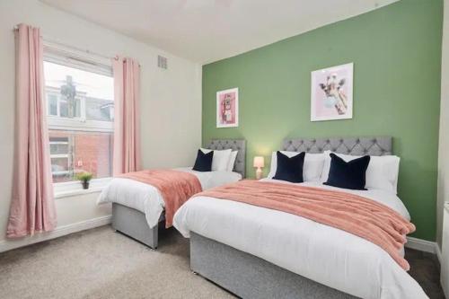 2 letti in una camera da letto con pareti verdi e finestra di The Bluebird B&B II a Headingley