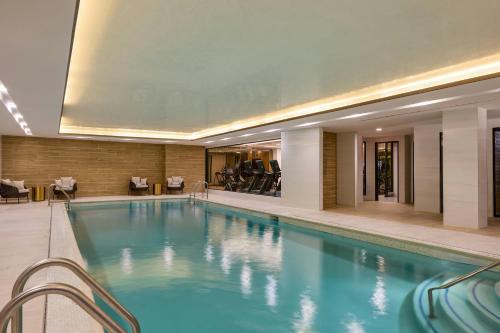 a pool in a hotel with chairs and tables at The Westin Flushing LaGuardia Airport in Flushing