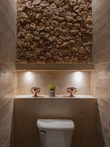 a bathroom with a toilet and a stone wall at Hotel Bernardino in Valladolid