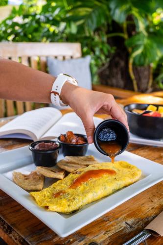 a person is pouring sauce onto a plate of food at El Xalli Hotel in El Zonte