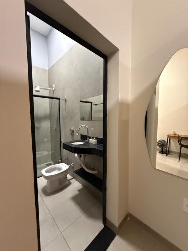 a bathroom with a toilet and a sink and a mirror at Loft Prime Andradina in Andradina