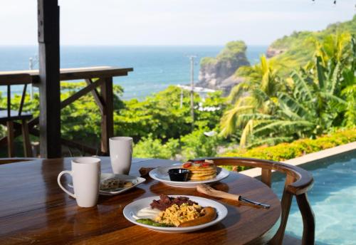 a table with two plates of food and a view of the ocean at El Xalli Hotel in El Zonte